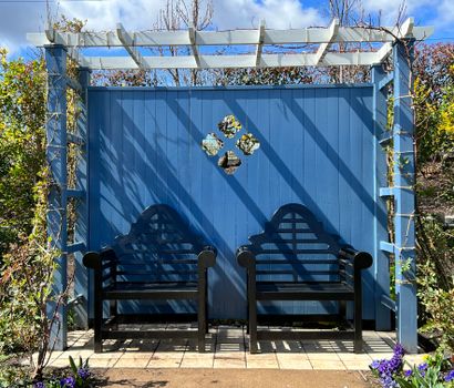 Compacte pergola in een kleine stadstuin in Noord-Holland met houten bank, klimplanten en sfeerverlichting